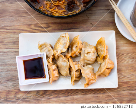 Grilled gyoza dumplings, bowl of soy sauce and chopsticks Grilled gyoza dumplings, bowl of soy sauce and chopsticks 136882718