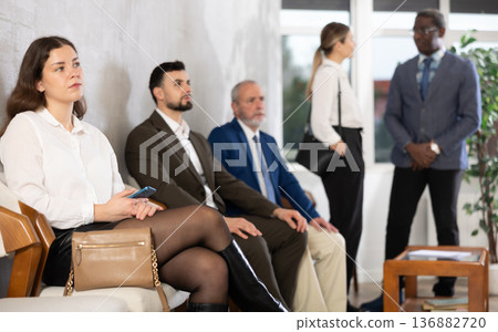 Applicants are waiting for interview, there is queue of people sitting in waiting room. Applicants are waiting for interview, there is queue of people sitting in waiting room. 136882720