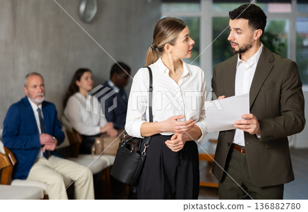 Young businessman with documents talks to female job seeker Young businessman with documents talks to female job seeker 136882780
