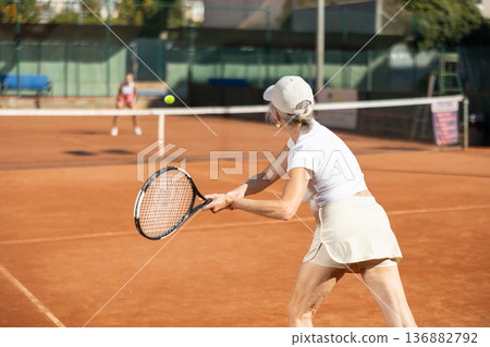 Elderly woman in sportswear playing tennis Elderly woman in sportswear playing tennis 136882792