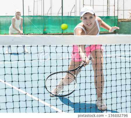 Portrait of young beautiful female tennis player about to serve ball. 136882796