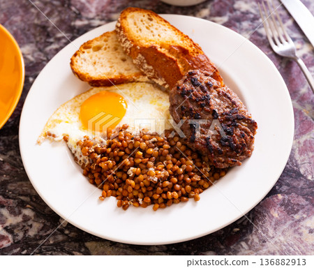 Hamburger cutlet with fried egg and lentils 136882913