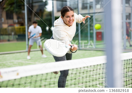 Sporty young girl playing padel on open court Sporty young girl playing padel on open court 136882918