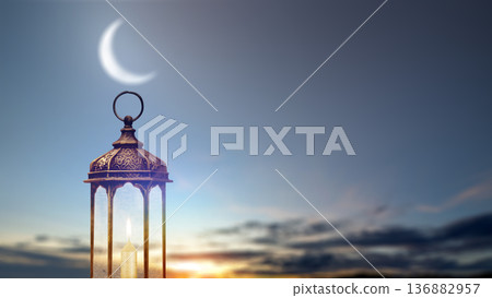Atmospheric image of a traditional Arabic lantern with a lit candle under a crescent moon at sunset. Perfect for Ramadan Kareem and Eid Mubarak greeting cards and backgrounds Atmospheric image of a traditional Arabic lantern with a lit candle under a crescent moon at sunset. Perfect for Ramadan Kareem and Eid Mubarak greeting cards and backgrounds 136882957
