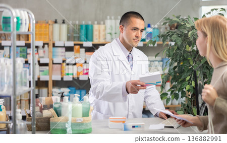 male pharmacist sells pills to a client male pharmacist sells pills to a client 136882991