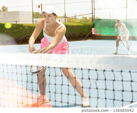 Young woman playing tennis with her teammate in court 136883042