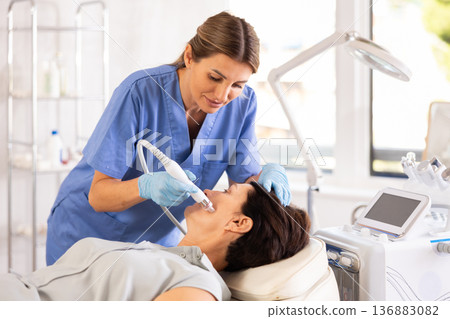 Female cosmetologist performing facial procedure on woman using ion bubble attachment 136883082