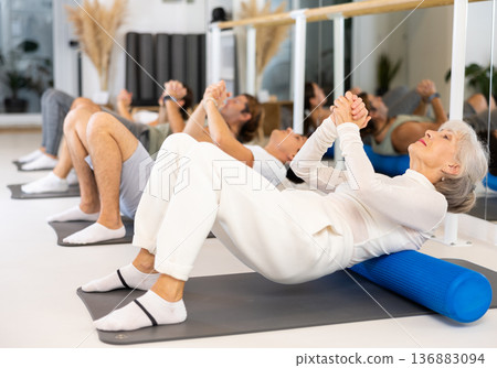 Group of different people doing exercises with roller 136883094