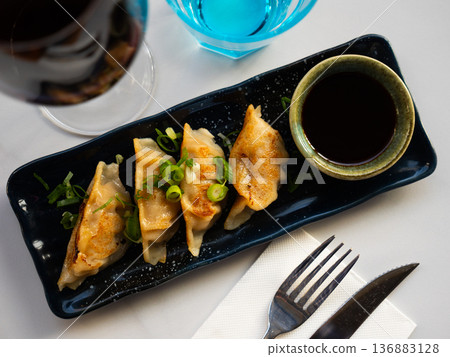 Grilled gyoza dumplings, bowl of soy sauce and chopsticks 136883128