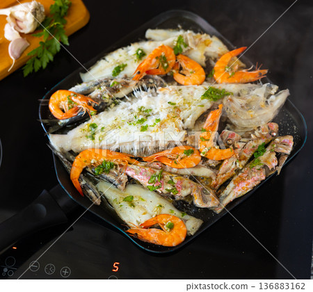 Assortment of seafood seasoned with green herb oil sizzling in skillet Assortment of seafood seasoned with green herb oil sizzling in skillet 136883162