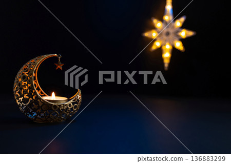 Ornamental Arabic lantern with burning candle glowing at night. Festive greeting card 136883299