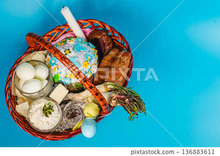 Easter basket with eggs, cake, and bread on blue background Easter basket with eggs, cake, and bread on blue background 136883611