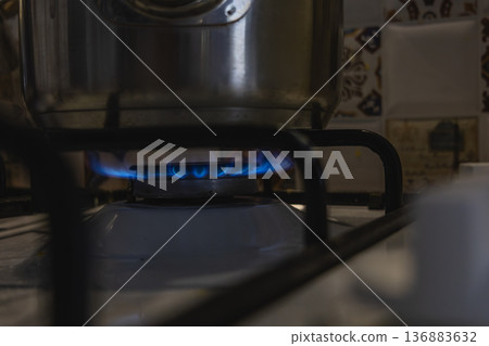 Burner with blue flame under pot on stove in kitchen at night Burner with blue flame under pot on stove in kitchen at night 136883632