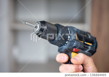 Cordless drill with screwdriver bit in hand close up Cordless drill with screwdriver bit in hand close up 136884405