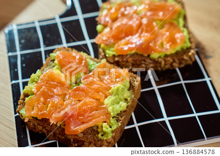 Two avocado toasts with smoked salmon on black grid serving board Two avocado toasts with smoked salmon on black grid serving board 136884578