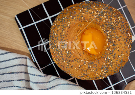 Top view seeded bagel with egg on black grid board with cloth napkin Top view seeded bagel with egg on black grid board with cloth napkin 136884581