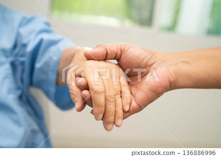 Caregiver holding hands Asian elderly woman patient, help and care in hospital. Caregiver holding hands Asian elderly woman patient, help and care in hospital. 136886996