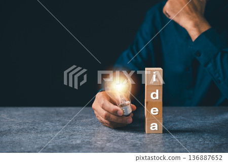 Business idea growth light bulb solution, marketing hand holding lightbulb, concept brings creative ideas using wooden blocks on dark textured stone office background Business idea growth light bulb solution, marketing hand holding lightbulb, concept brings creative ideas using wooden blocks on dark textured stone office background 136887652