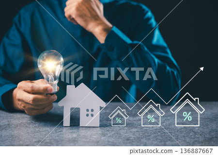 Man holding glowing light bulb near house model shows real estate innovation, energy savings plus creative idea for home mortgage property and lightbulb electricity knowledge 136887667