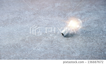 Lightbulb bulb light idea concept creative innovation business design radiates on grey stone surface representing inspiration smart thinking solutions with success at hand 136887672