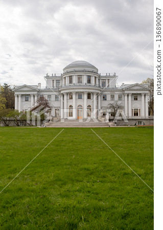 Elegantly Designed White Mansion Surrounded by Green Grass Under a Cloudy Sky in a Serene Setting Elegantly Designed White Mansion Surrounded by Green Grass Under a Cloudy Sky in a Serene Setting 136890067