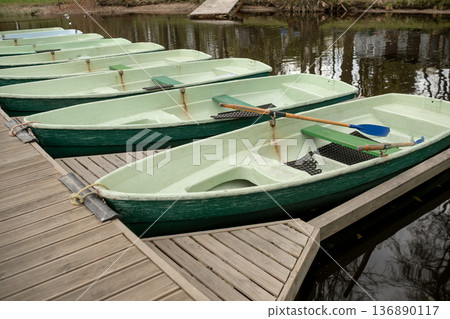 Rowboats Moored at a Wooden Dock by a Peaceful River During Early Spring Afternoon Rowboats Moored at a Wooden Dock by a Peaceful River During Early Spring Afternoon 136890117