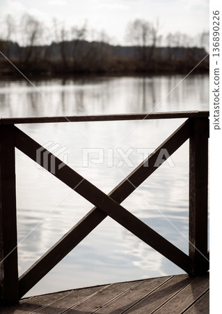 Wooden Railing Overlooking Calm Water Under Soft Cloudy Sky at Dawn Wooden Railing Overlooking Calm Water Under Soft Cloudy Sky at Dawn 136890226