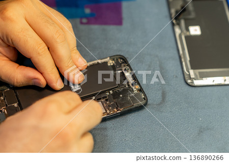 Expert Phone Repair Technician Replacing Battery in a Modern Smartphone at a Workshop Expert Phone Repair Technician Replacing Battery in a Modern Smartphone at a Workshop 136890266