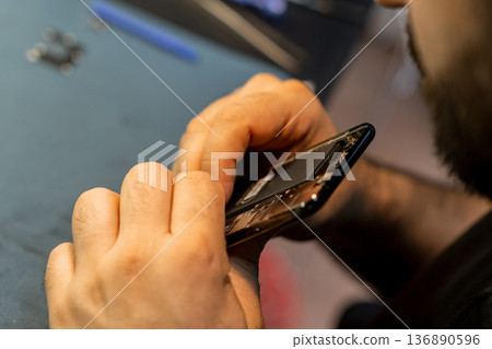 Expert Technician Repairing a Smartphone in a Busy Phone Repair Shop During Afternoon Hours Expert Technician Repairing a Smartphone in a Busy Phone Repair Shop During Afternoon Hours 136890596