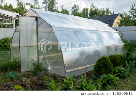 Greenhouse Made of Transparent Panels in a Garden Setting on a Sunny Day Offers Ideal Conditions for Plant Growth and Cultivation Greenhouse Made of Transparent Panels in a Garden Setting on a Sunny Day Offers Ideal Conditions for Plant Growth and Cultivation 136890611