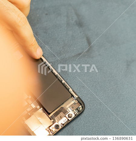 Expert Repair Technician Works on Smartphone Battery Replacement With Precision and Skill in a Clean Workspace During Daytime 136890631