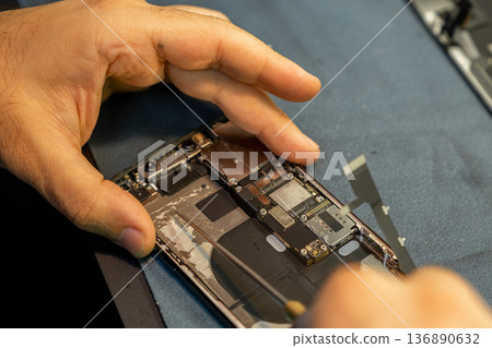 Expert Phone Repair in Progress With Detailed Attention to Internal Components at a Workshop 136890632