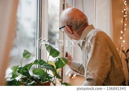 Elderly man waiting quietly by window in solitude. Elderly man waiting quietly by window in solitude. 136891345