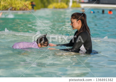 slow motion of preschool child girl learning to diving with her mother in swimming pool slow motion of preschool child girl learning to diving with her mother in swimming pool 136891382