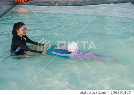 preschool child girl learning to swim with board with mother in swimming pool preschool child girl learning to swim with board with mother in swimming pool 136891397