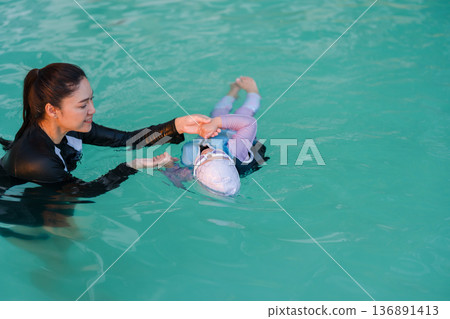 preschool child girl in life jacket learning to swim with mother in swimming pool preschool child girl in life jacket learning to swim with mother in swimming pool 136891413