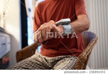 Senior man measuring blood pressure with wrist monitor. 136891431
