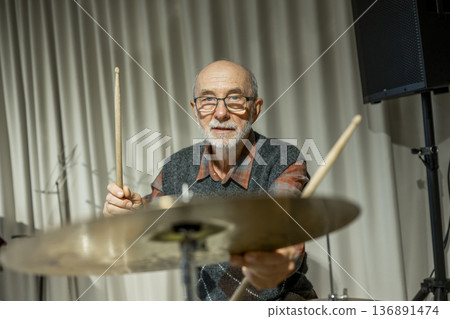 Senior man enjoying his hobby playing drums. Senior man enjoying his hobby playing drums. 136891474