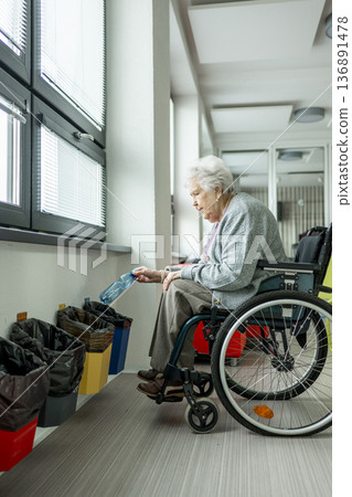 Senior woman in wheelchair sorting plastic bottle for recycling. Senior woman in wheelchair sorting plastic bottle for recycling. 136891478