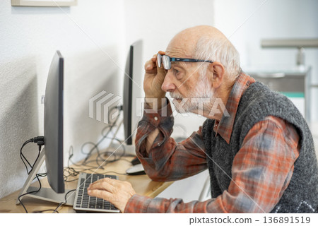 Senior man working on computer at desk. 136891519