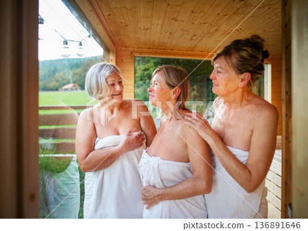 Group of mature women enjoying sauna session and wellness ritual. 136891646