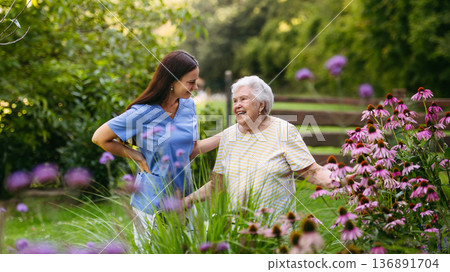 Home nurse spending time with elderly lady patient in garden. 136891704