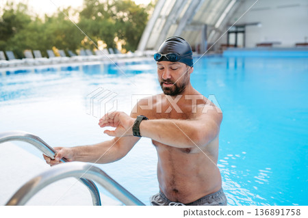 Male swimmer getting out of the pool after swim training. 136891758