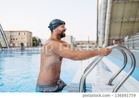 Male swimmer getting out of the pool after swim training. 136891759