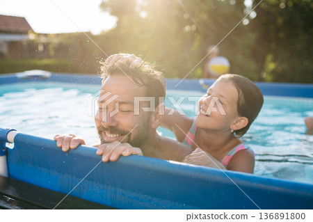 Father playing with young daughter in pool. 136891800