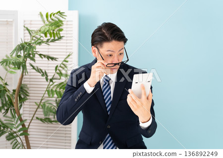 一臉驚訝的男子拿著計算器 136892249