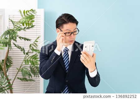 Surprised man holding a calculator 136892252