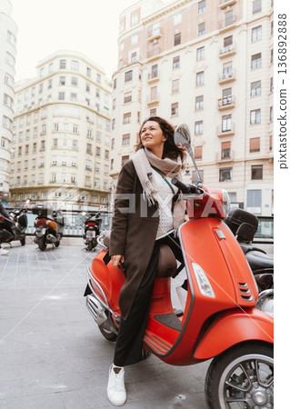 Woman Relaxing on Red Scooter in City Street Woman Relaxing on Red Scooter in City Street 136892888