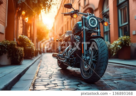 Sleek motorcycle parked on cobblestone street bathed in golden s 136893168