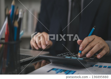 Accountant hand holding pencil use calculator. Business finance concept. Man working office desk, check financial report, data analysis graph, calculate budget, investment savings, paperwork. 136895660